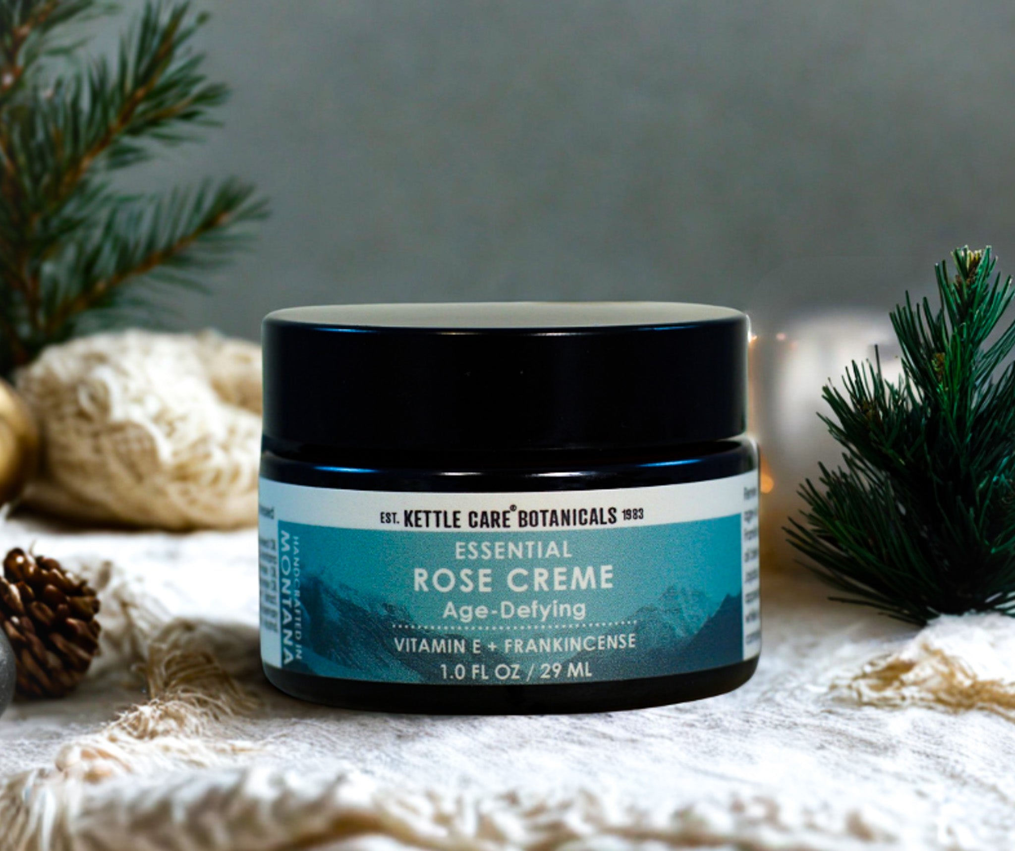 Jar of Kettle Care Botanicals Essential Rose Creme on a textured surface with decorative elements.